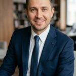 Портрет уверенного российского бизнесмена с дружелюбным взглядом на нейтральном размытом фоне студии